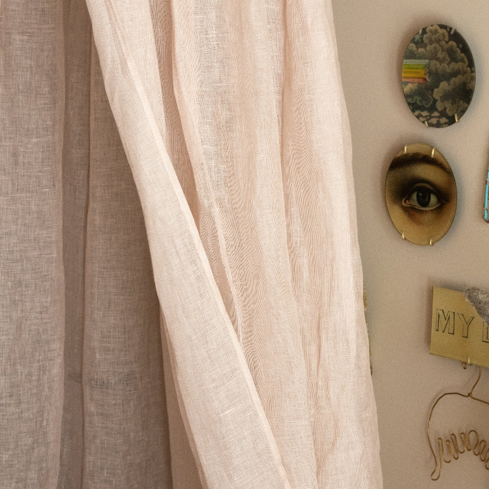 Sheer beige curtain with decorative wall art in the background