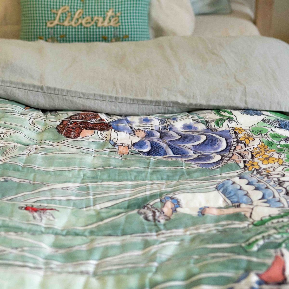 A reversible quilted blanket illustrated with a pond scenery, day on one side and night on the other.
