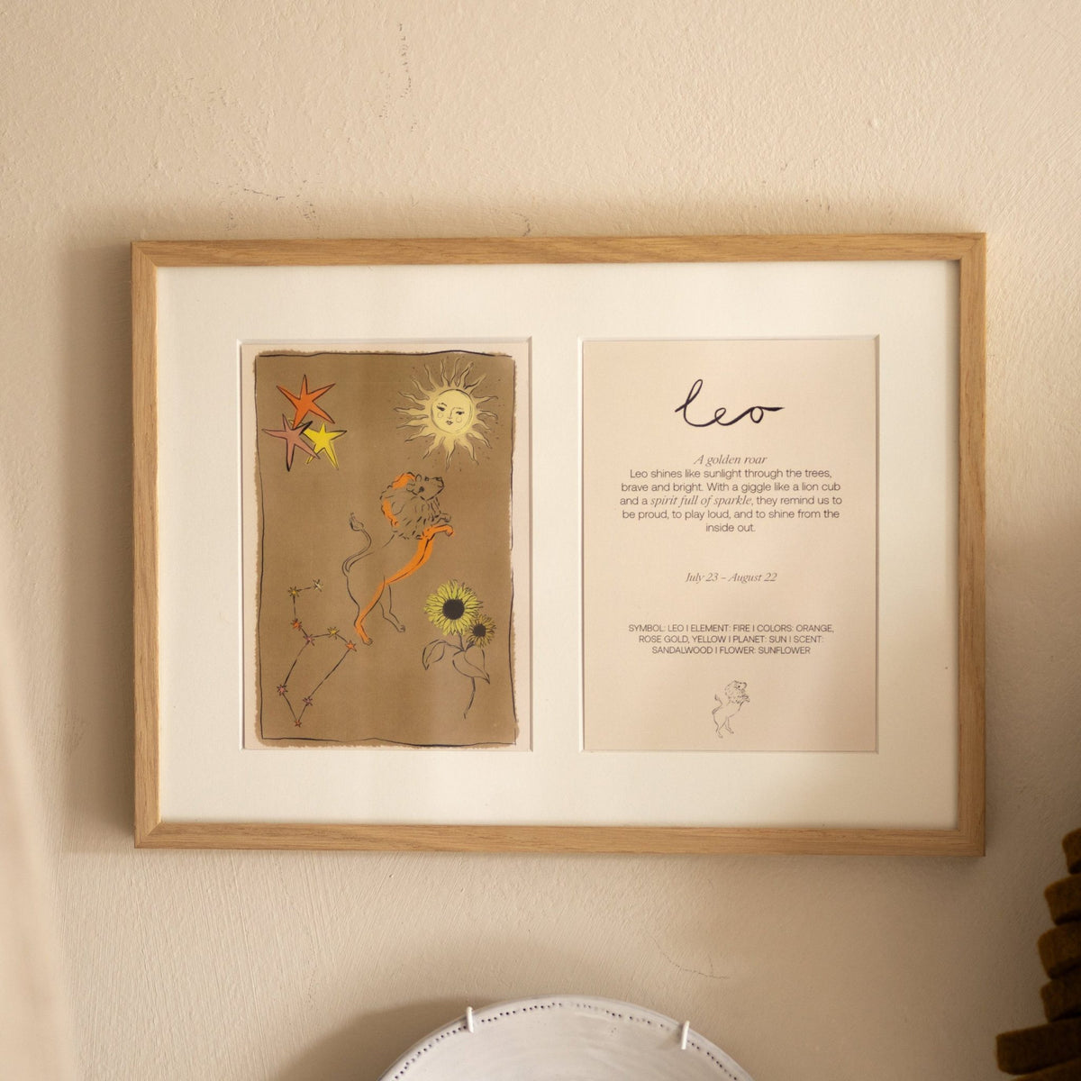 Ingelijste dubbele Hazel & George Leeuw-poster aan de wand in een lichte houten lijst