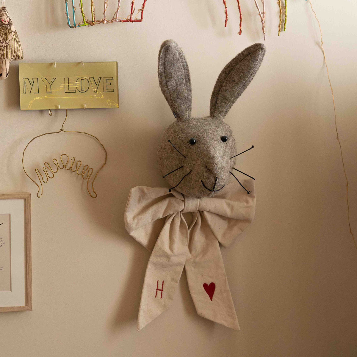 Hazel & George Canvas Festive Bow Small tied around a plush rabbit head wall decoration, styled with other nursery wall decor