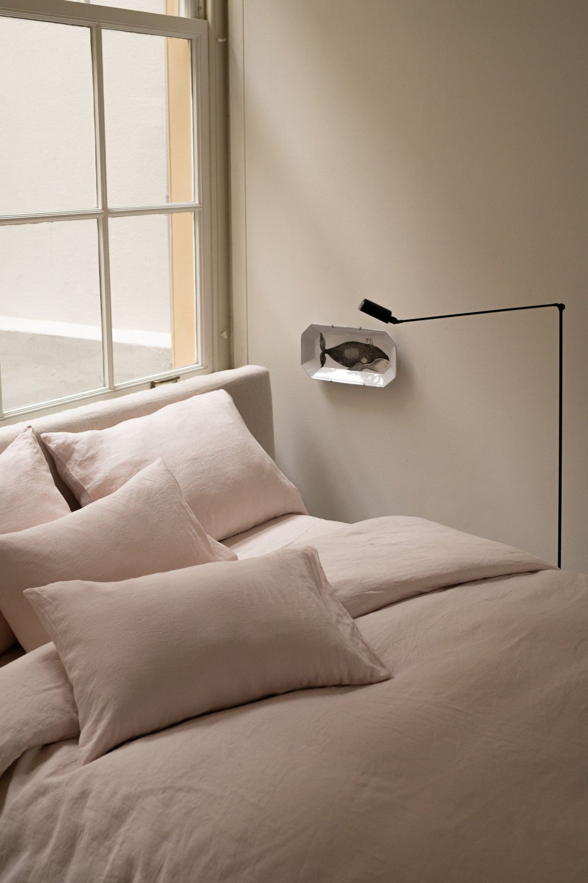 Hazel & George Linen Duvet Cover in Craie on a bed, with pillows near a window