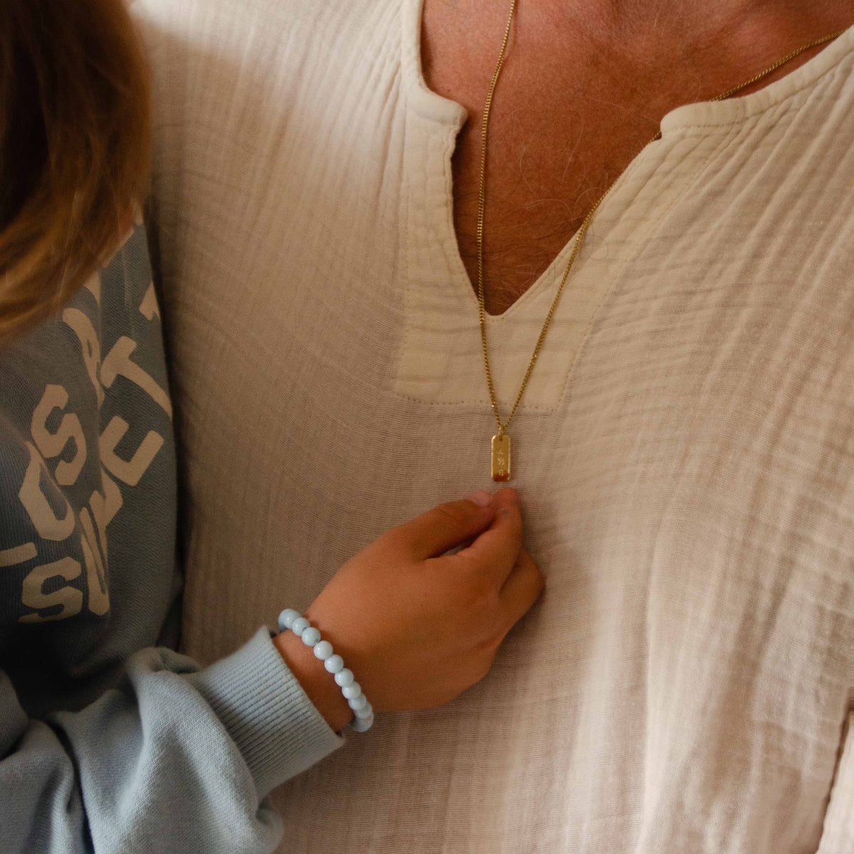Hazel & George Rectangular Initial Hanger 14K Gold, father wearing the rectangular gold pendant necklace while a child&