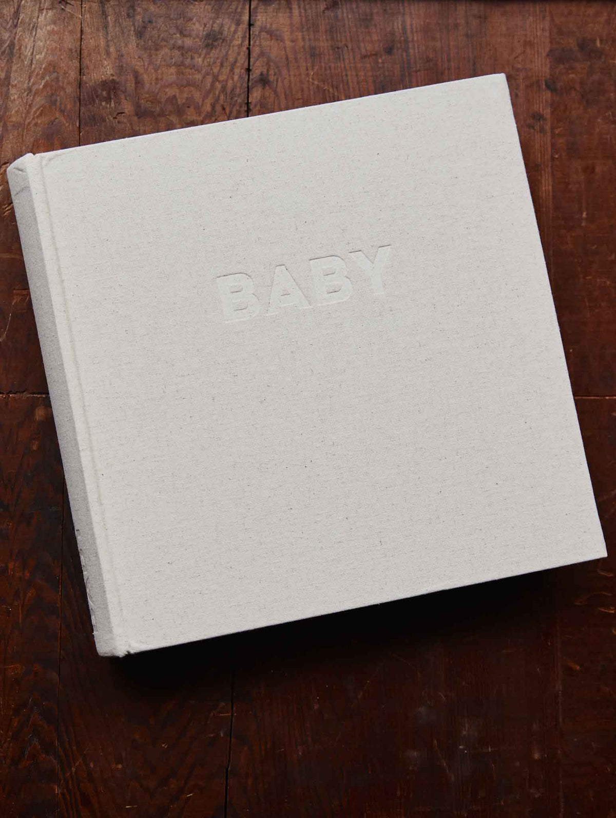 Write to me Fotoalbum Classic Baby met naturel linnen kaft en BABY in reliëf, op een houten tafel