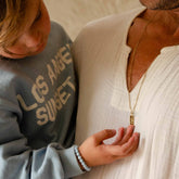Hazel & George Necklace 14K Gold - 60 cm, father wearing a long gold necklace with a rectangular pendant while his child holds his hand