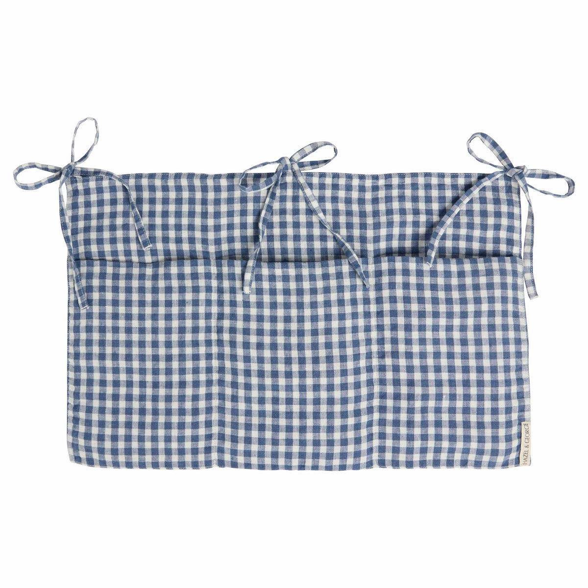 Hazel &amp; George Linen Bed Pocket in Vichy, a linen storage pocket in blue-and-white check with three ribbon ties and three compartments, on a white background