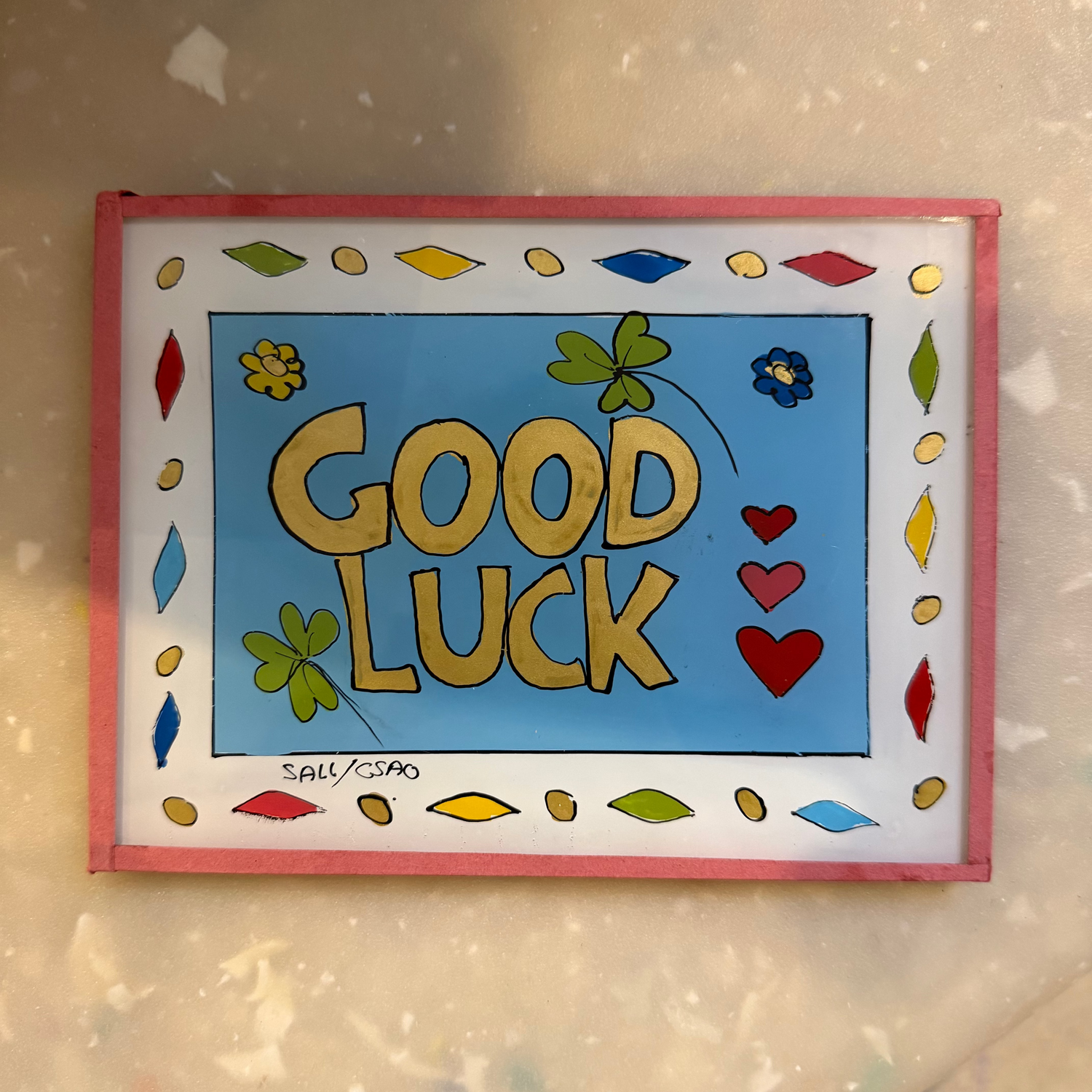 A rectangular hand-painted card with the words &
