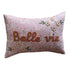 Decorative pillow with floral patterns and embroidered text on a beige surface.