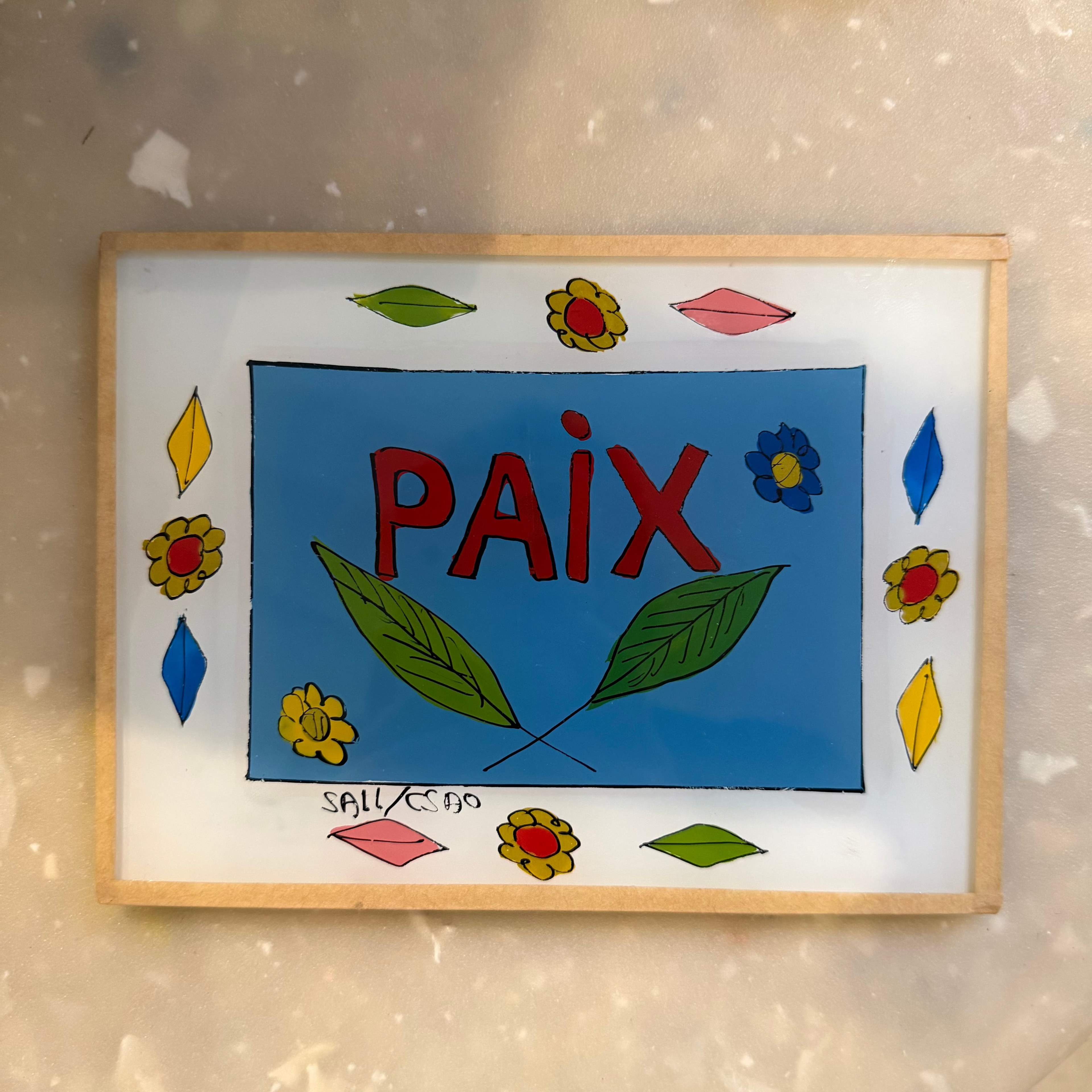 A square glass art plaque featuring a colorful hand-painted design with the word &