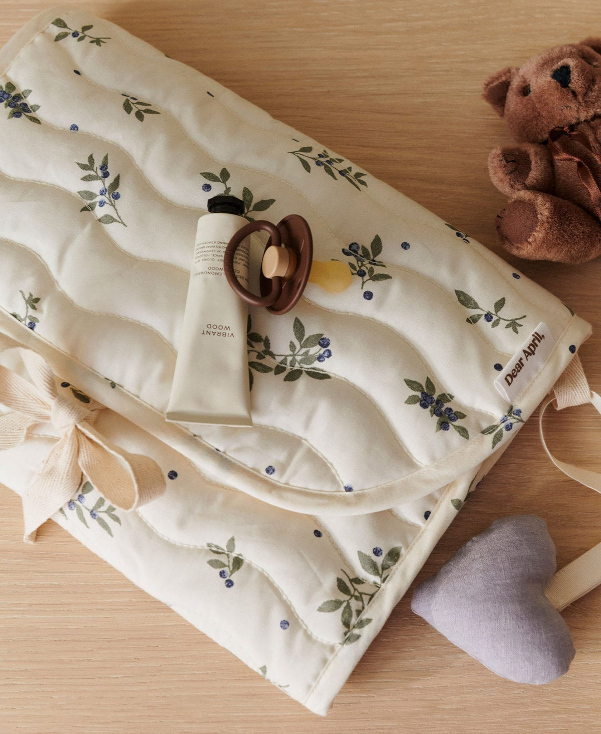 Dear April Change To Go Blueberries changing mat with a heart-shaped toy, styled with a teddy bear and hand cream