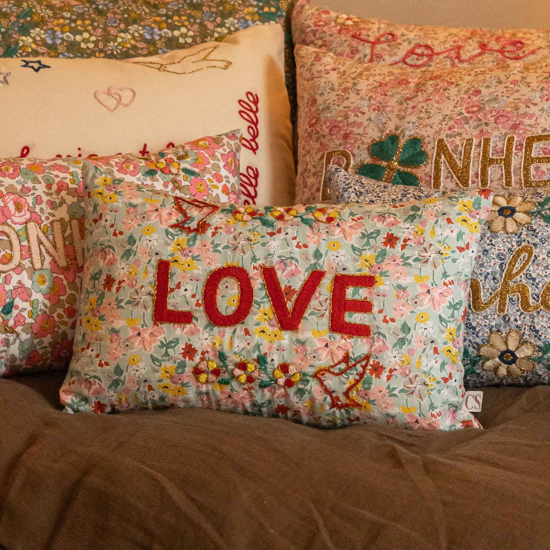 Decorative pillows with floral patterns and embroidered text.