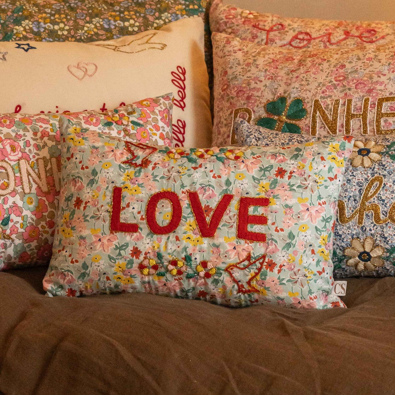 Decorative pillows with floral patterns and embroidered text.