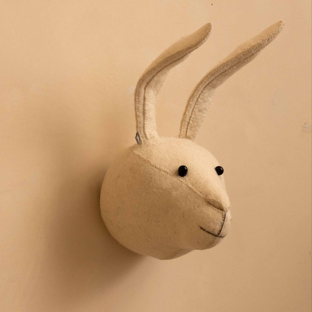 A cream-colored felt rabbit head wall mount with long upright ears