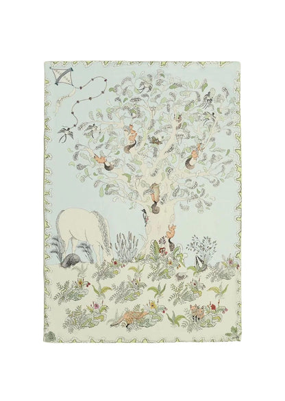 A reversible baby muslin swaddle illustrated with a whimsical forest scene, showing daytime on one side and a magical night scene on the other.