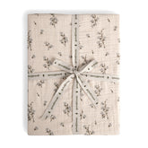 A folded fitted sheet with a floral pattern, tied with a ribbon.