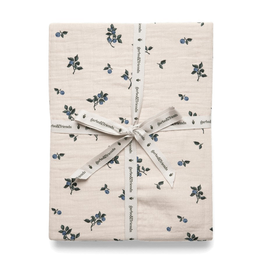Folded fitted sheet with blueberry pattern, wrapped with ribbon and tag displaying the brand name.