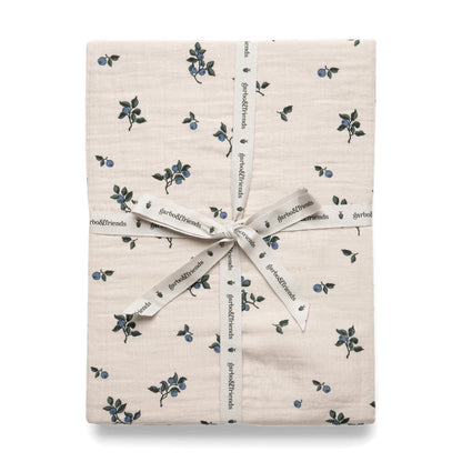 Folded fitted sheet with blueberry pattern, wrapped with ribbon and tag displaying the brand name.