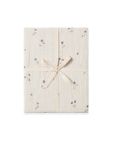 A folded Viola Muslin Fitted Sheet with a subtle floral pattern, tied with a ribbon.