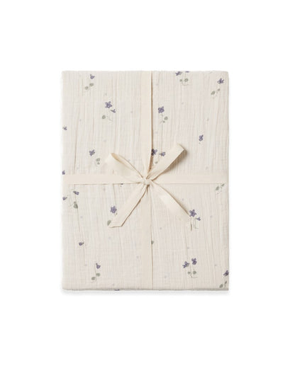 A folded Viola Muslin Fitted Sheet with a subtle floral pattern, tied with a ribbon.