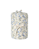 A rolled fabric item, likely a blanket or throw, featuring a delicate blue and gray floral print on a warm cream background, tied with a matching cream ribbon.