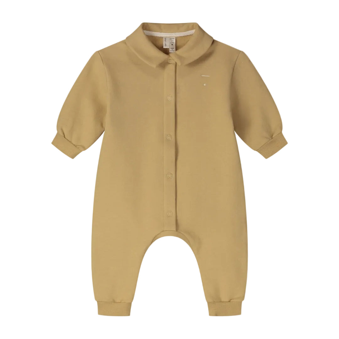 A baby long-sleeve romper in a warm mustard yellow color, featuring a button-up front, a small embroidered logo on the left chest, and a pointed collar.