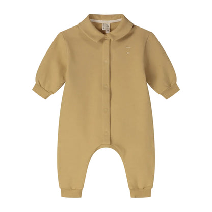 A baby long-sleeve romper in a warm mustard yellow color, featuring a button-up front, a small embroidered logo on the left chest, and a pointed collar.