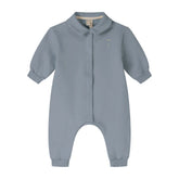 A baby long-sleeve romper in a dusty slate blue color, featuring a Peter Pan collar, snap-button front, and cuffed ankles.