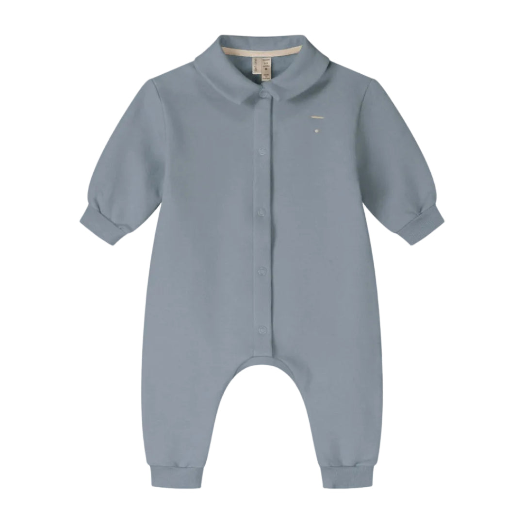 A baby long-sleeve romper in a dusty slate blue color, featuring a Peter Pan collar, snap-button front, and cuffed ankles.