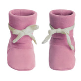 A pair of pink knit baby booties with white ribbon bows tied around the ankles