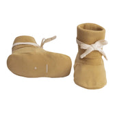 A pair of tan knit booties with white ribbon bows, shown from both the side and top