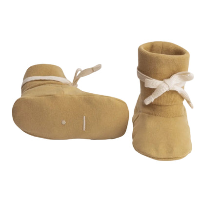 A pair of tan knit booties with white ribbon bows, shown from both the side and top
