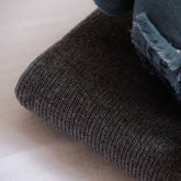Close-up of the folded edge of a Hazel & George Georgia Merino Blanket in Charcoal, showing the ribbed knit texture