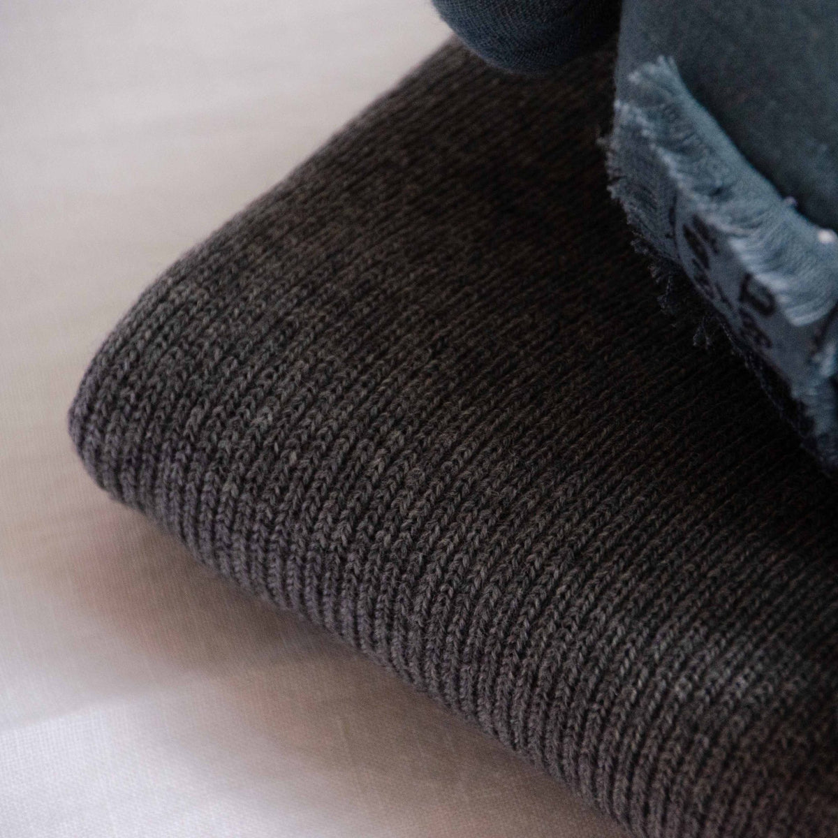 Close-up of the folded edge of a Hazel &amp; George Georgia Merino Blanket in Charcoal, showing the ribbed knit texture