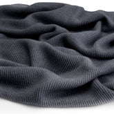 Close-up of the knitted merino wool fabric of a Hazel & George Merino Blanket in Charcoal, draped to show texture