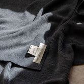 Close-up of the Hazel & George label and care instructions on a Merino Blanket in Charcoal