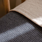 Close-up of a Hazel & George Georgia Merino Blanket in Charcoal draped over a wooden crib rail