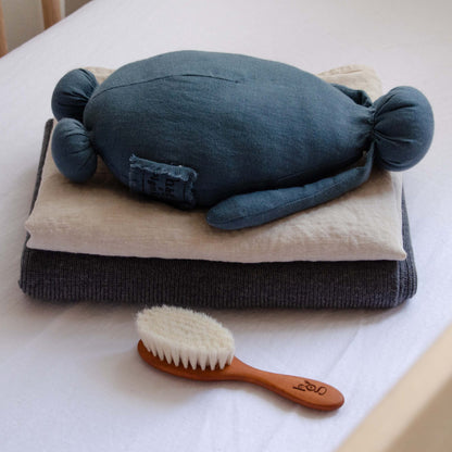 Folded Hazel &amp; George Hazel Merino Baby Blanket in Charcoal, styled with a plush toy and a wooden baby hair brush