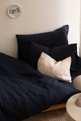 Hazel & George Linen Duvet Cover in Off Black on a single bed, with a contrasting cream pillow