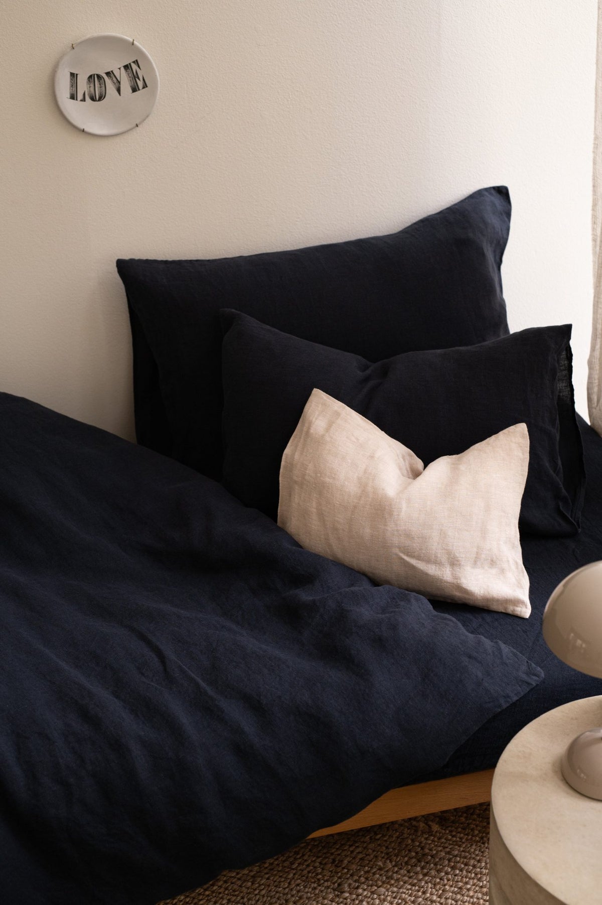 Hazel &amp; George Linen Duvet Cover in Off Black on a single bed, with a contrasting cream pillow