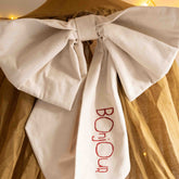 Detail of the Hazel & George Personalized Festive Bow Large in cream, showing the &
