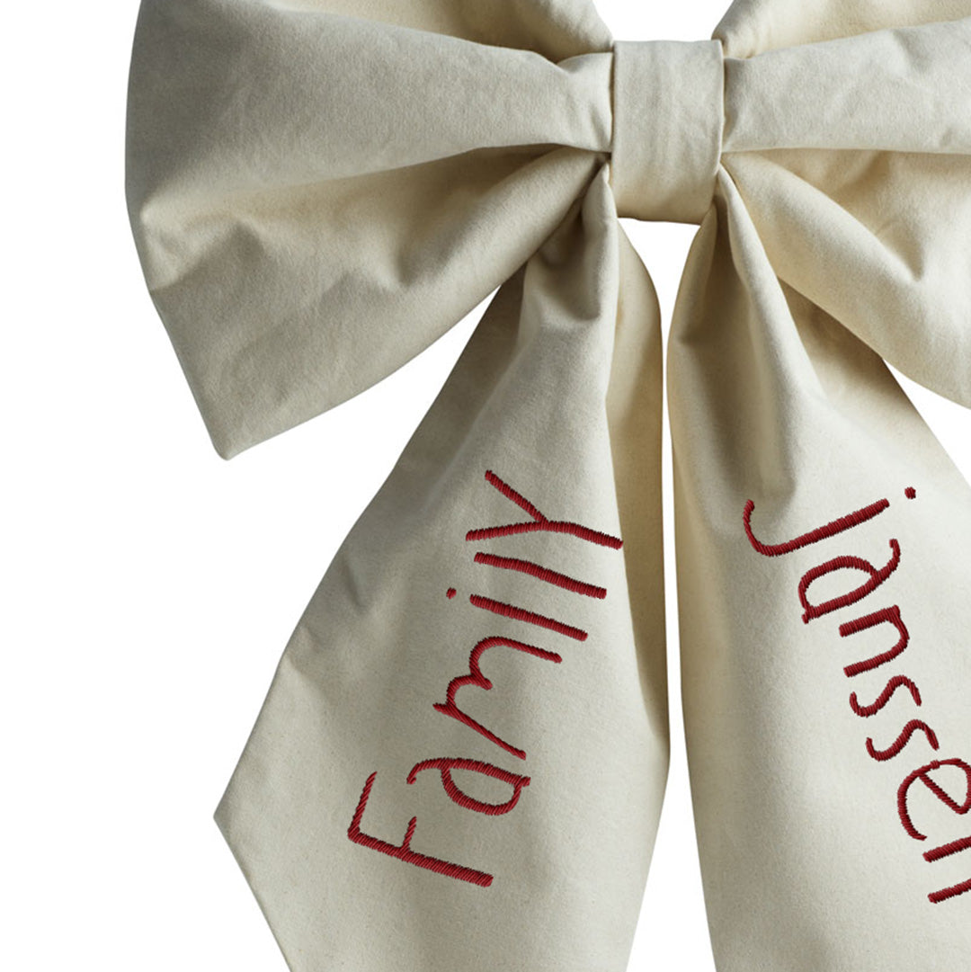 Close-up van de Hazel &amp; George Personalized Festive Bow Large in de kleur crème, met de borduring &