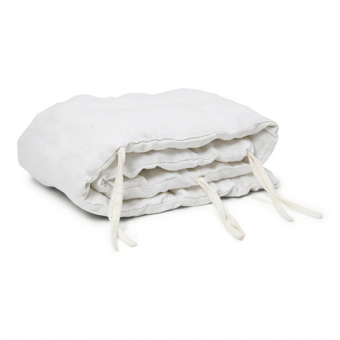 Hazel &amp; George Linen Cover for Cot Bumper in Blanc, a padded linen bumper roll with white ties, folded on a white background