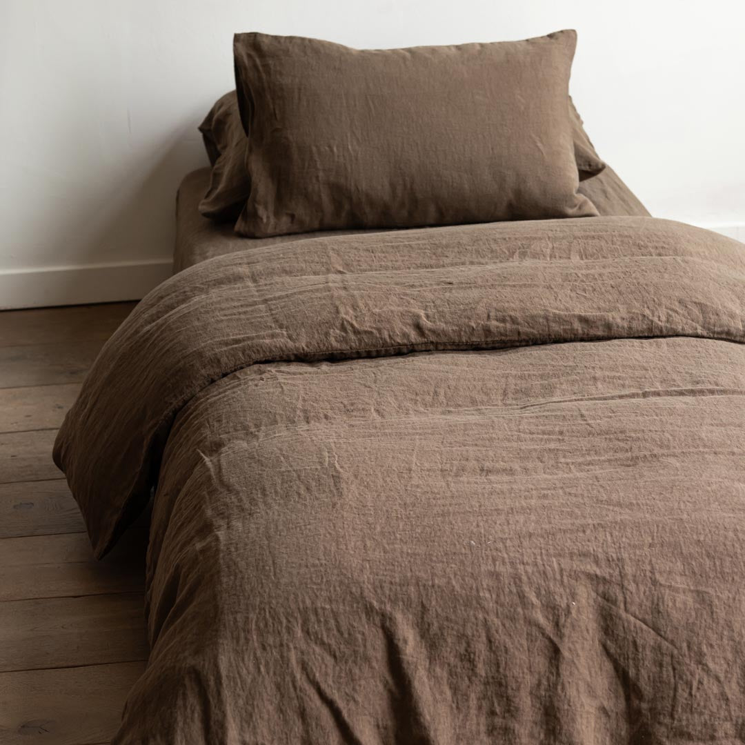 Brown textured bedding set on a bed against a white wall.