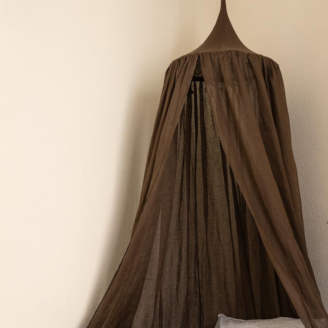 Brown curtain hanging against a beige wall
