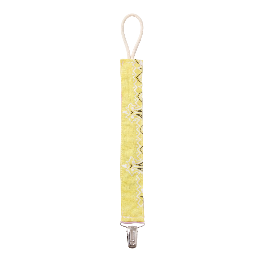 A yellow fabric baby clip with a white loop strap and a silver metal clip, featuring a yellow, white and black geometric pattern.