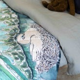 A reversible quilted blanket illustrated with a pond scenery, day on one side and night on the other.