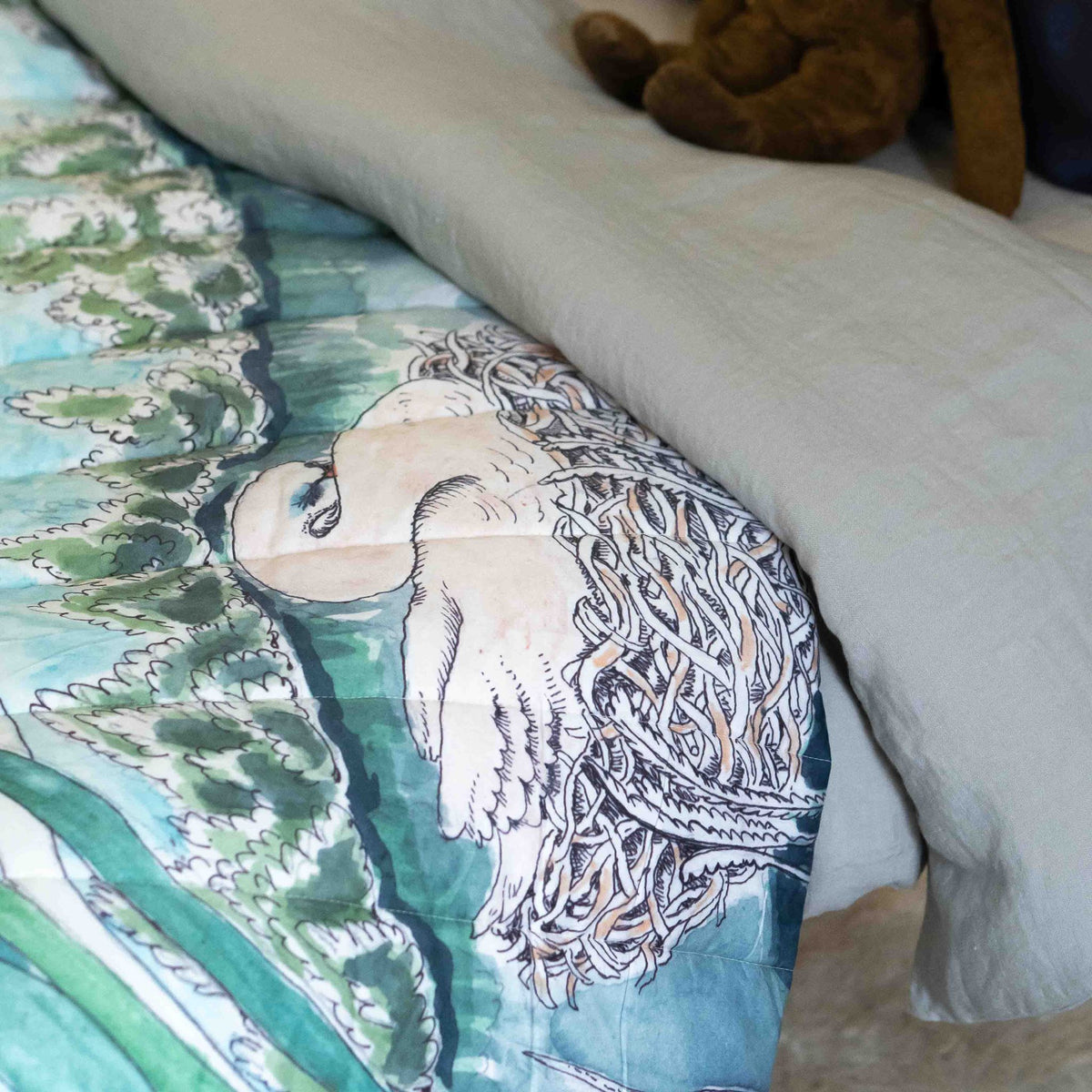 A reversible quilted blanket illustrated with a pond scenery, day on one side and night on the other.