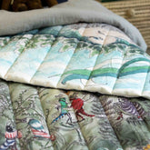 A reversible quilted blanket illustrated with a pond scenery, day on one side and night on the other.