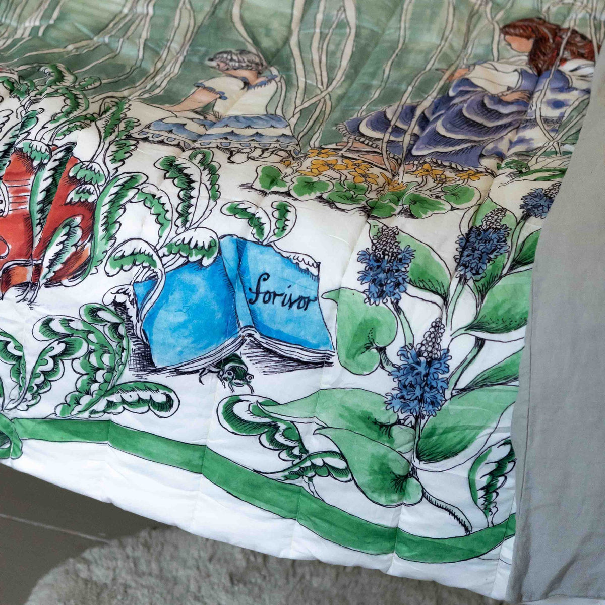 A reversible quilted blanket illustrated with a pond scenery, day on one side and night on the other.