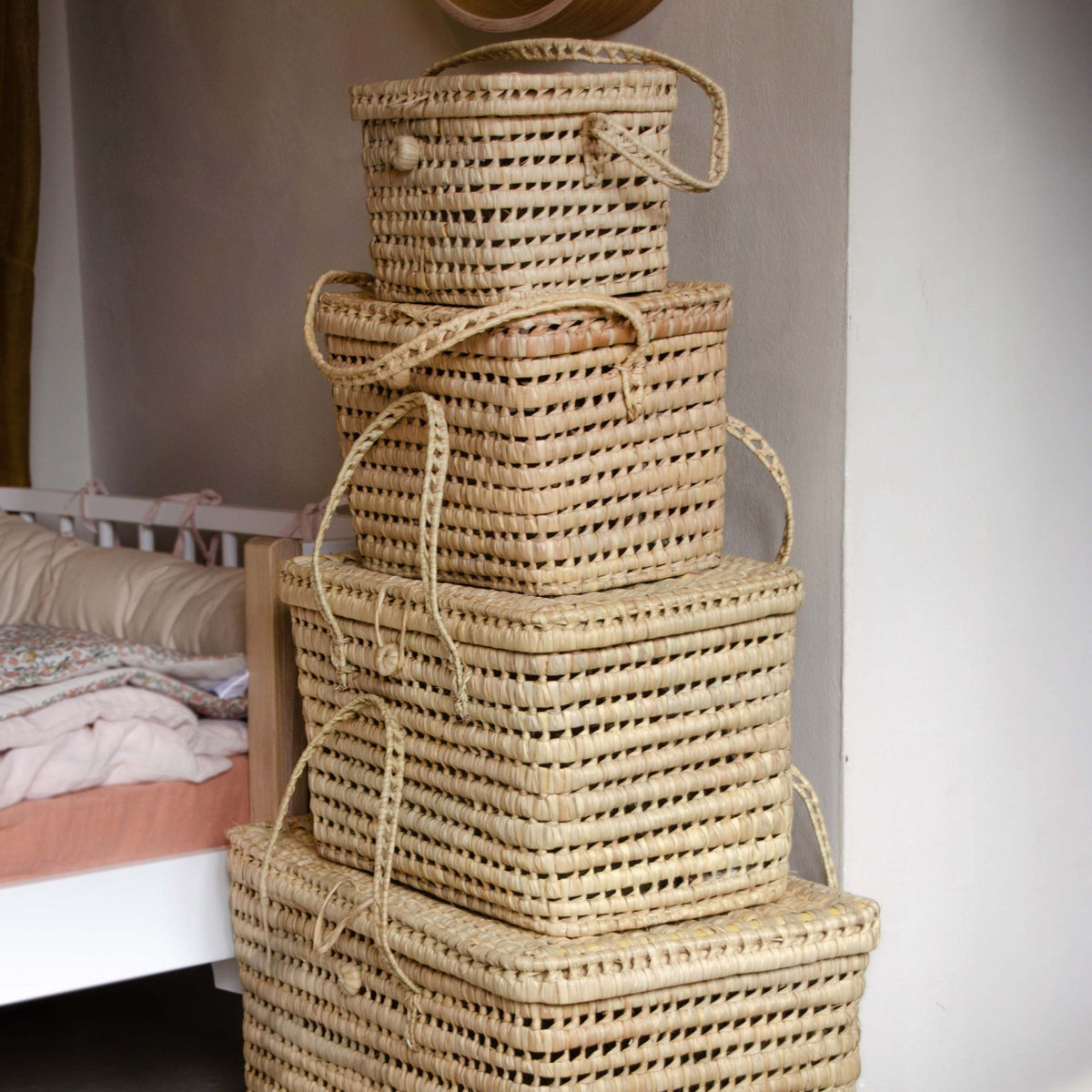 Three natural palm leaf baskets with lids from Tine K Home, styled in a nursery corner