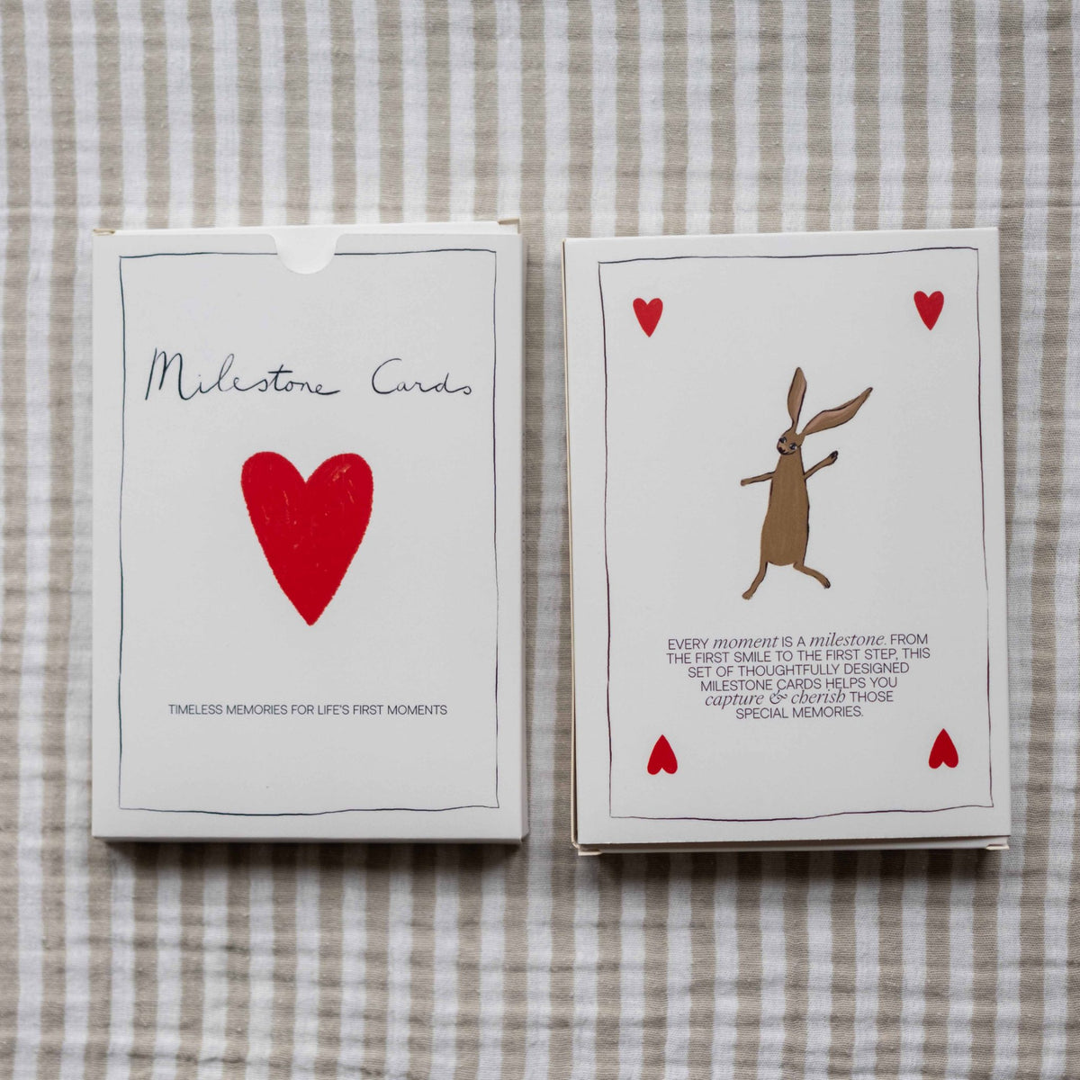 Two Milestone Cards boxes lying on striped linen fabric